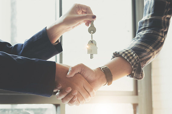 Two people shaking hands and one of them handing over keys
